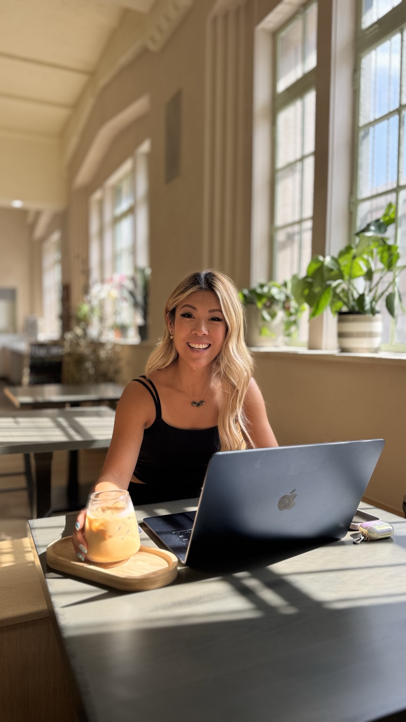Laura Law smiling while working at her laptop in a sunlit room